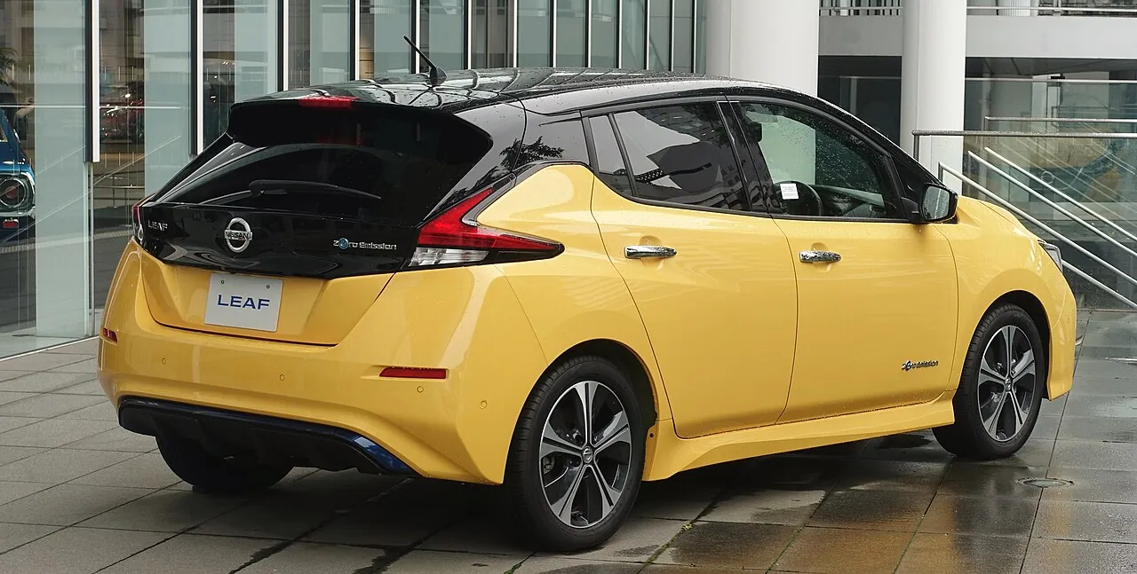 Nissan Leaf ZE1 жёлтого цвета с чёрной крышей, вид сзади и сбоку